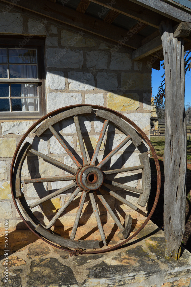 Antique wagon wheel leaning on an old western house.