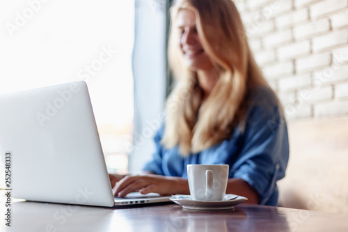 Young beautiful blonde girl 20 years working with laptop in cafe. Modern freelancer online business concept. Generation Z © olezzo