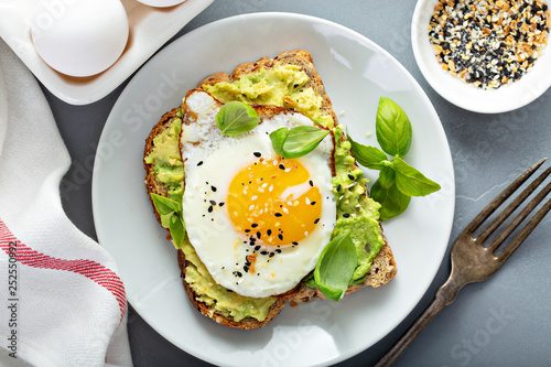 Schilderij op canvas Avocado toast with fried sunny side up egg overhead view