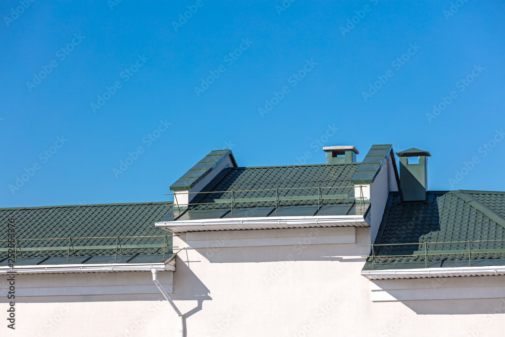 Fototapeta premium new green metal roof with drainpipe system on blue sky background