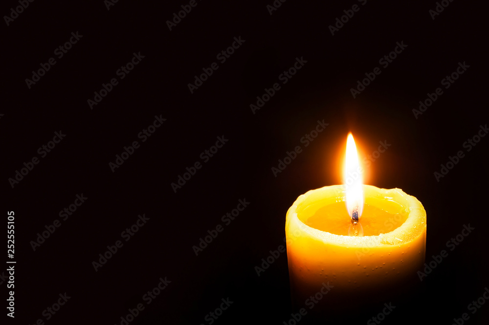 Single Burning Yellow Candle Glowing on a Dark Background. Copy Space. Single Burning Yellow Candle Glowing on a Dark Background. Copy Space.