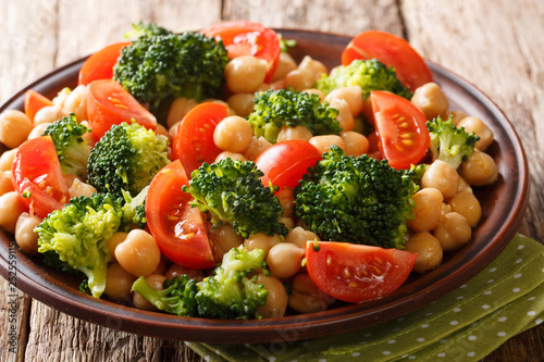 Organic vegetarian salad of broccoli, chickpeas and tomatoes with olive oil closeup on a plate. horizontal