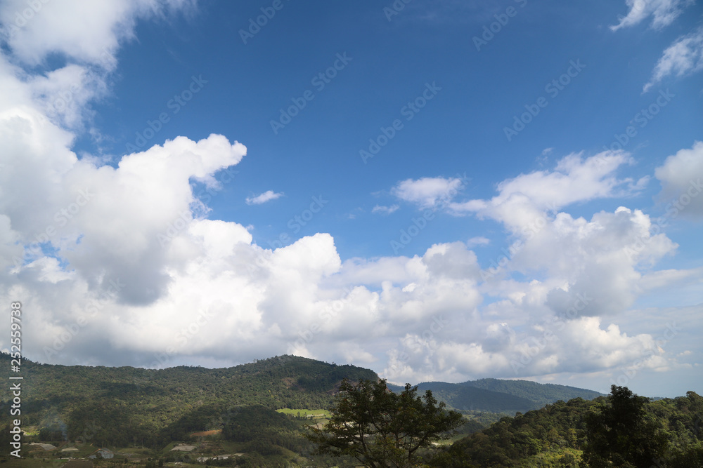 Scenery of tropical mountainous landscape with bright cloudy blue sky.