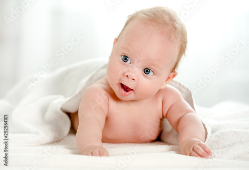 Newborn baby with beautiful blue eyes lying on belly