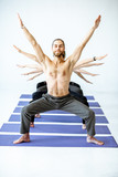 Man with naked torso standing in a yoga pose with multiple arms of other people behind on the white background