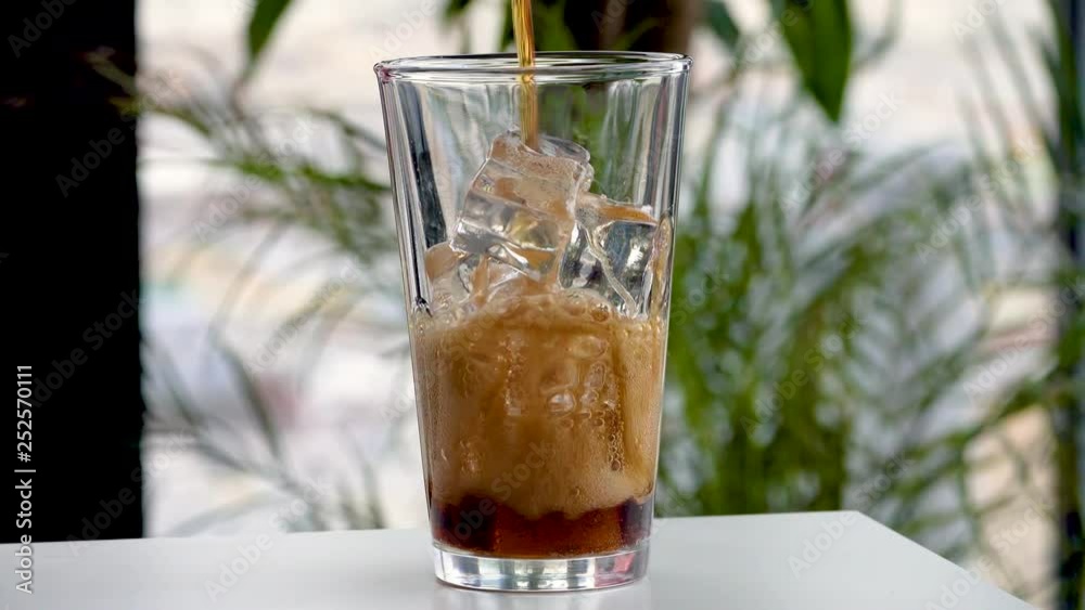 Pouring coke/cola/soda into a ice filled glass