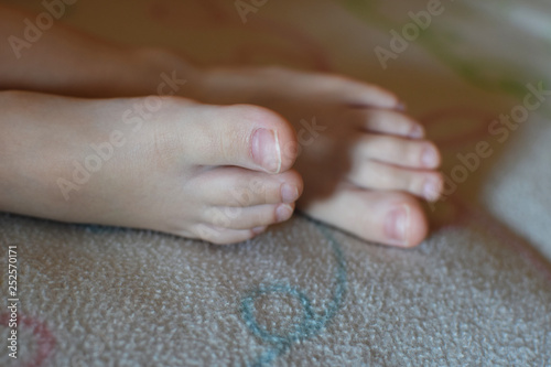 Closeup of child boy bare feet laying on blanket on bed.