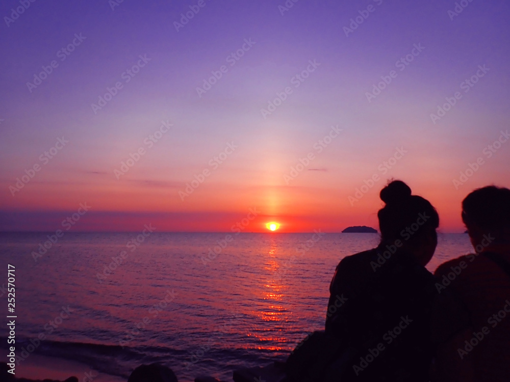 Romantic couple sitting together with the beautiful sunset.