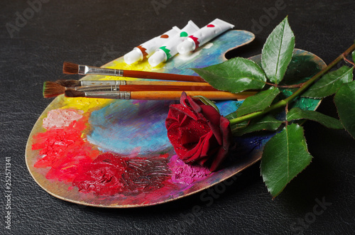 Fototapeta Naklejka Na Ścianę i Meble -  Art palette, brushes, paints, red roses on a dark. Close-up