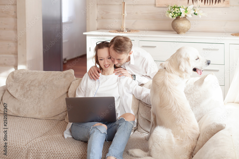 Happy young couple surfing the internet with a laptop and looking for a suitable hotel for dogs during the summer holidays Happy young couple surfing the internet with a laptop and looking for a suitable hotel for dogs during the summer holidays