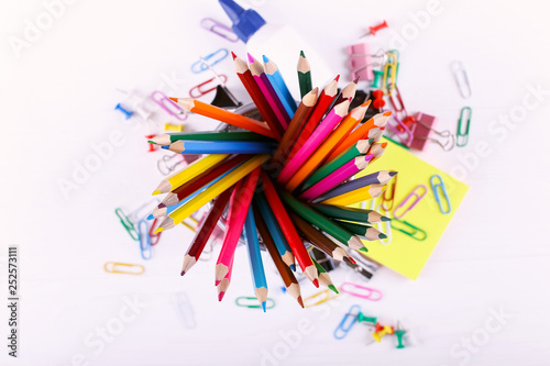 Colored pencils, paper clips and pins, school supplies for drawing, pattern, copy space.