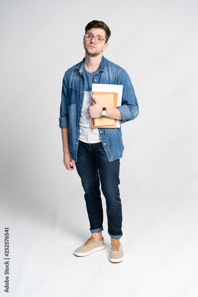 Happy young student standing full length with books and notes isolated on white background. Happy young student standing full length with books and notes isolated on white background.