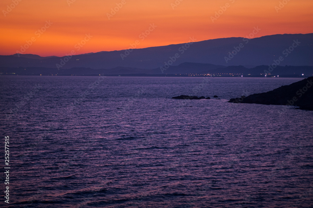 Sunset on the ionian sea. red and orange sun on blue water