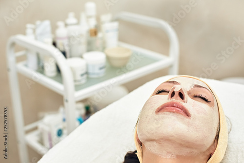 Portrait of attractive young woman lying in beauty salon with mask on her face