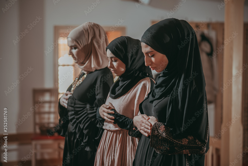 Three muslim girls pray together in mosque