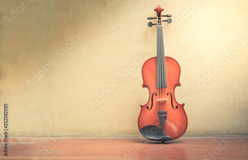 Wooden violin with old wall and wood floor.