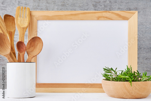 Kitchen utensils background with empty white paper and wooden cutlery in cup on a white table, kitchen mockup photo