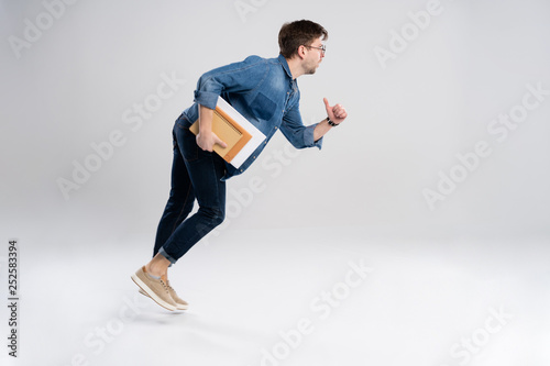 Full length portrait of a happy excited man jumping and looking at camera isolated over white background.