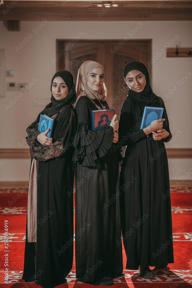 Three muslim girls reading Quran in mosque