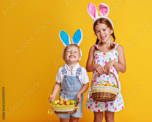 Wall Mural funny happy child boy with easter eggs and bunny ears on yellow.