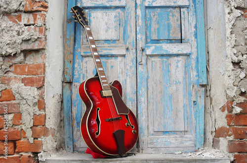 Jazz guitar in the window opening on the background of blue shutters © yrafoto