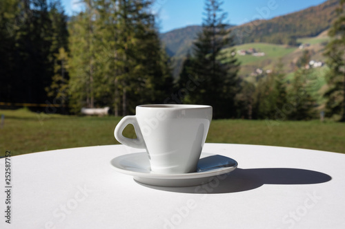 White cup of coffee in outdoor setting. Summer oudoor coffee break