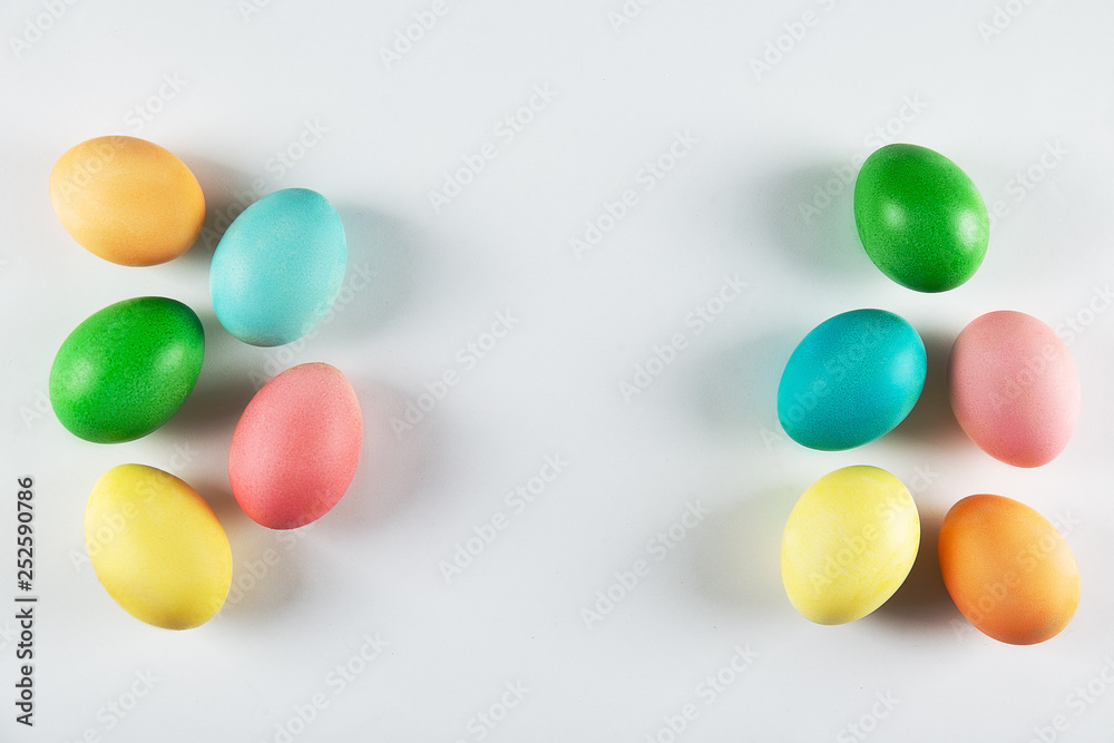 Bunch of blank painted Easter eggs of different pastel color on pale gray isolated background with a lot of copy space for text. Top view, flat lay, close up.