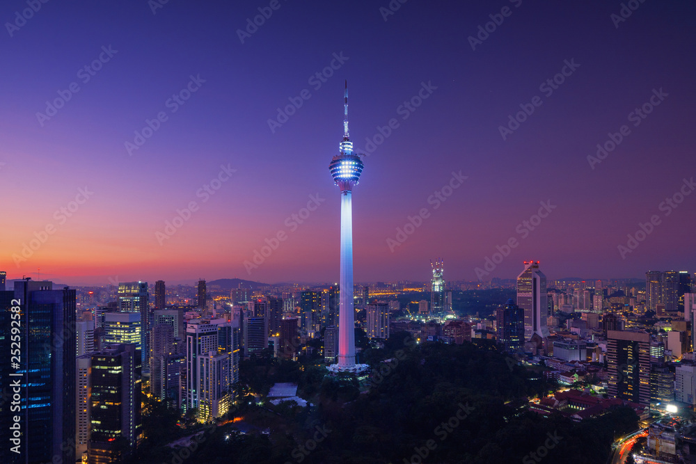 Obraz premium Menara Kuala Lumpur Tower w nocy. Widok z lotu ptaka centrum Kuala Lumpur, Malezja. Dzielnica finansowa i centra biznesowe w azjatyckim mieście miejskim. Wieżowiec i wieżowce w południe.