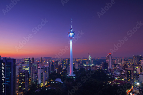 Menara Kuala Lumpur Tower at night. Aerial view of Kuala Lumpur Downtown, Malaysia. Financial district and business centers in urban city in Asia. Skyscraper and high-rise buildings at noon.
