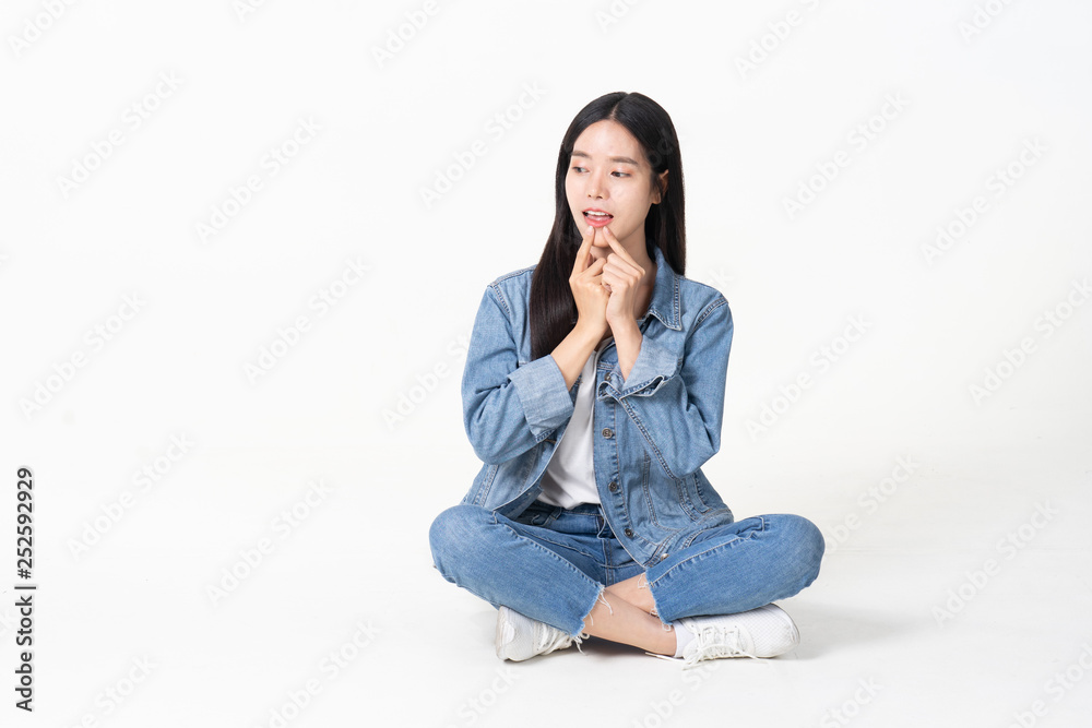 Thinking asian woman sitting on floor isolated on white background.Asian female model smiling looking up.woman pointing fingers away while sitting on a floor with legs crossed isolated Thinking asian woman sitting on floor isolated on white background.Asian female model smiling looking up.woman pointing fingers away while sitting on a floor with legs crossed isolated