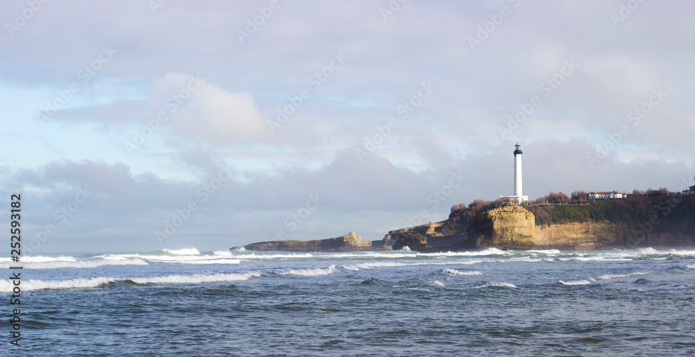 Picturesque old lighthouse on a cliff and ocean with waves