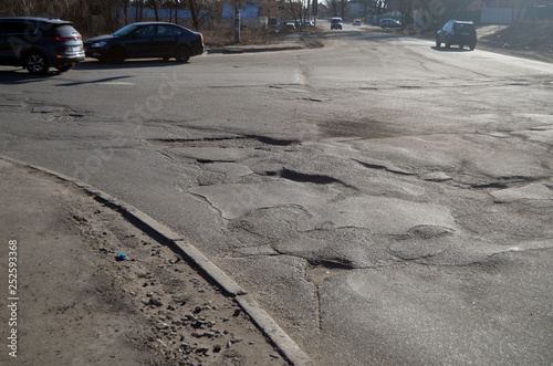 Poor condition of the road surface. Winter season. Hole in the asphalt, risk of movement by car, bad asphalt, dangerous road, potholes in asphalt.  Kiev,Ukraine photo