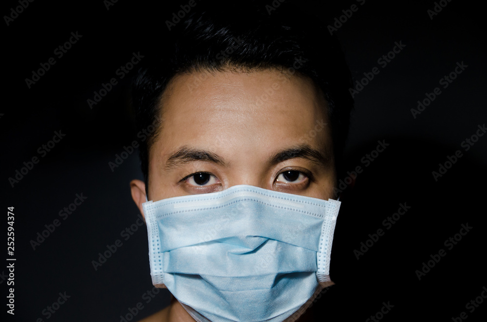 close up of young asian man wearing hygienic mask with dark blackground close up of young asian man wearing hygienic mask with dark blackground