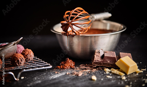 Chocolate coated whisk resting on mixing bowl photo