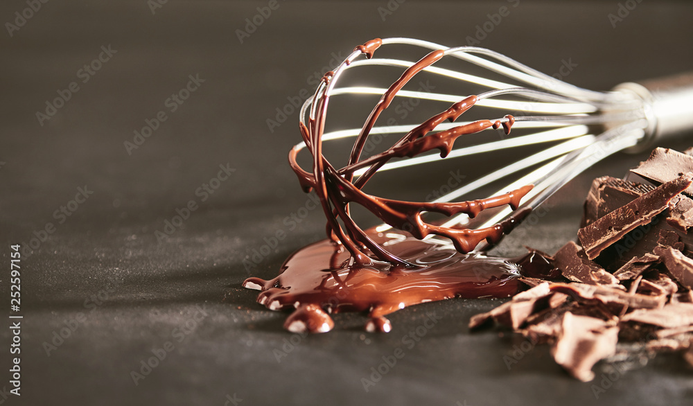 Melted dairy chocolate dripping off an old whisk