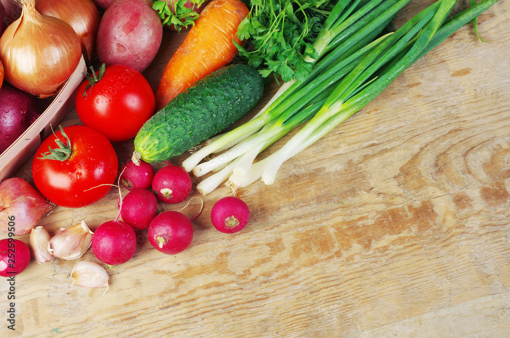 Appetizing vegetables on a wooden table. Green onions, tomatoes, cucumbers, carrots, radishes, garlic, parsley. Appetizing vegetables on a wooden table. Green onions, tomatoes, cucumbers, carrots, radishes, garlic, parsley.