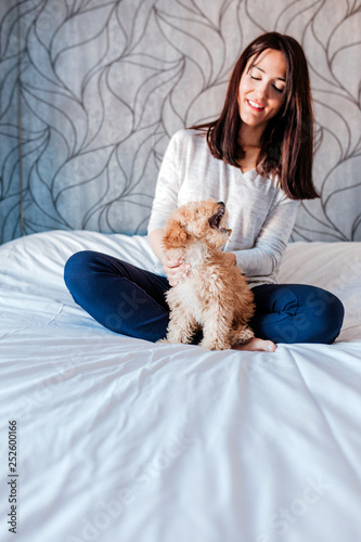 portrait of a Cute brown toy poodle with his young woman owner at home, daytime, indoors.