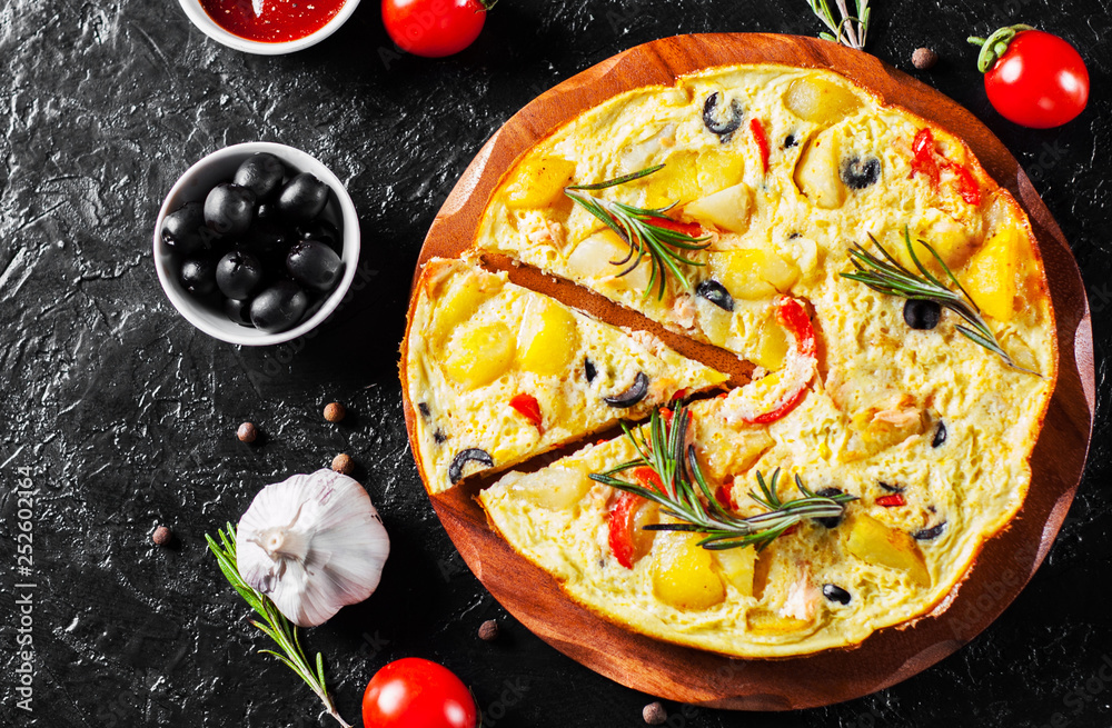 omelette with salmon fish, vegetables and olive in a plate on dark background