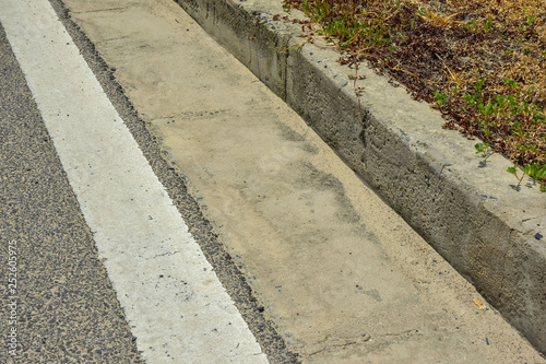 concrete curb close-up on the asphalt roadway. drain along the road