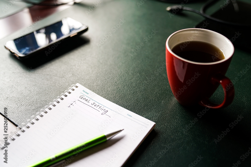 Goals setting to be written on a notebook with a green pen Goals setting to be written on a notebook with a green pen