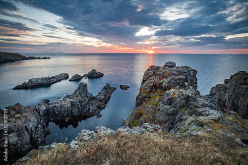 Dramatic sunrise with beautiful clouds over the Black Sea with very steep rocks in the foreground.
