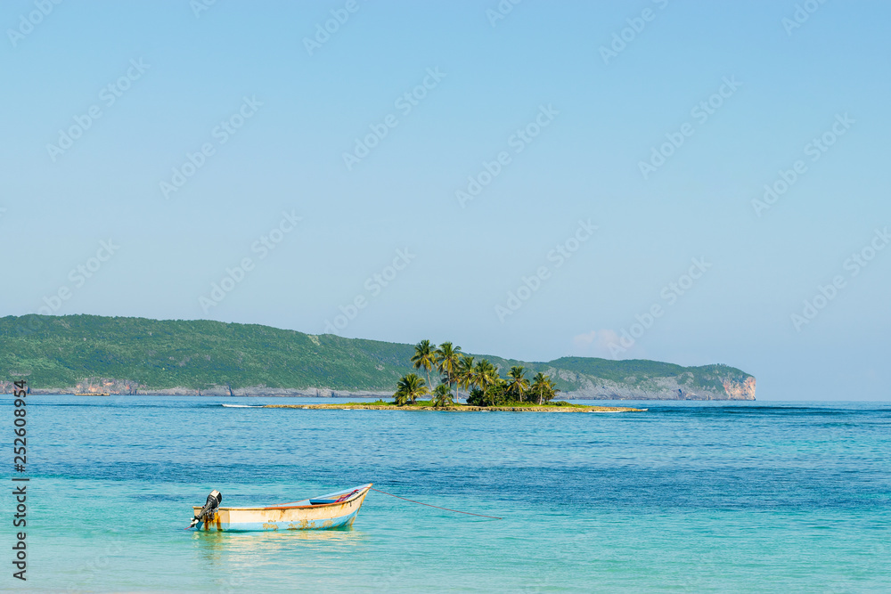 Landscape od turquoise sea and small tropical island with palm trees and fisherman boat in Las Galeras- Dominican Republic. 