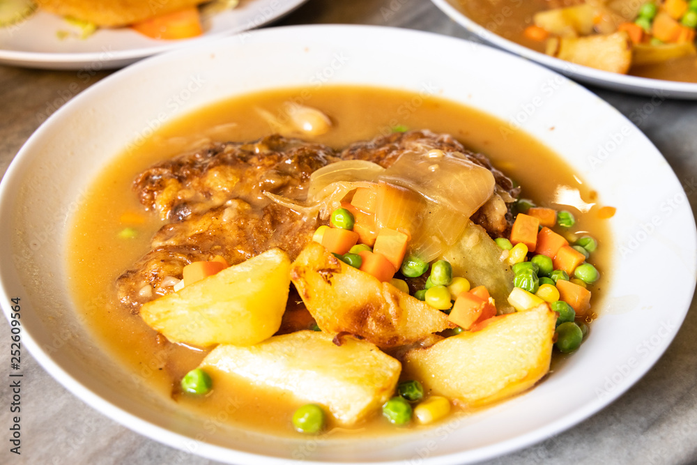 Serving of hainanese chicken chop with gravy, peas, carrots, potatoes. Serving of hainanese chicken chop with gravy, peas, carrots, potatoes.