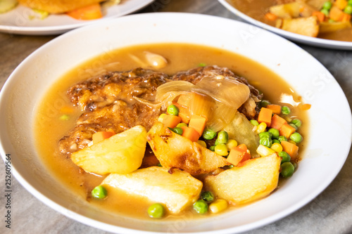 Serving of hainanese chicken chop with gravy, peas, carrots, potatoes.