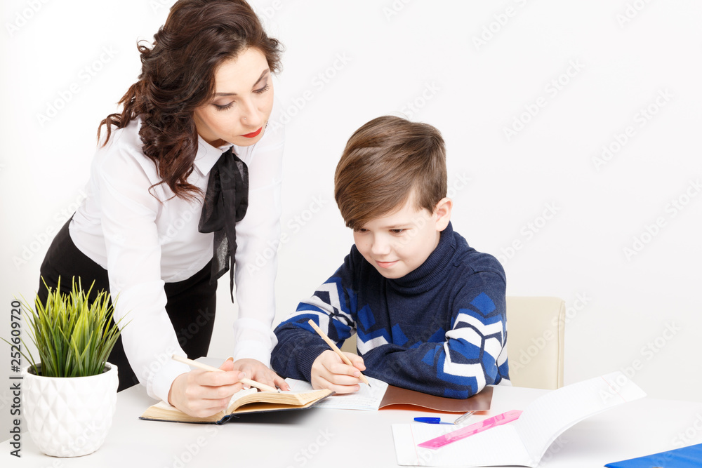 Female teacher helps teen boy to do his homework. Doing homework together Female teacher helps teen boy to do his homework. Doing homework together