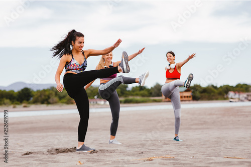 Group of young women is warming up before jogging on the beach by the sea