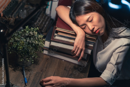 tired asian office woman work hard sleepless all night work with ton of book and documents on table