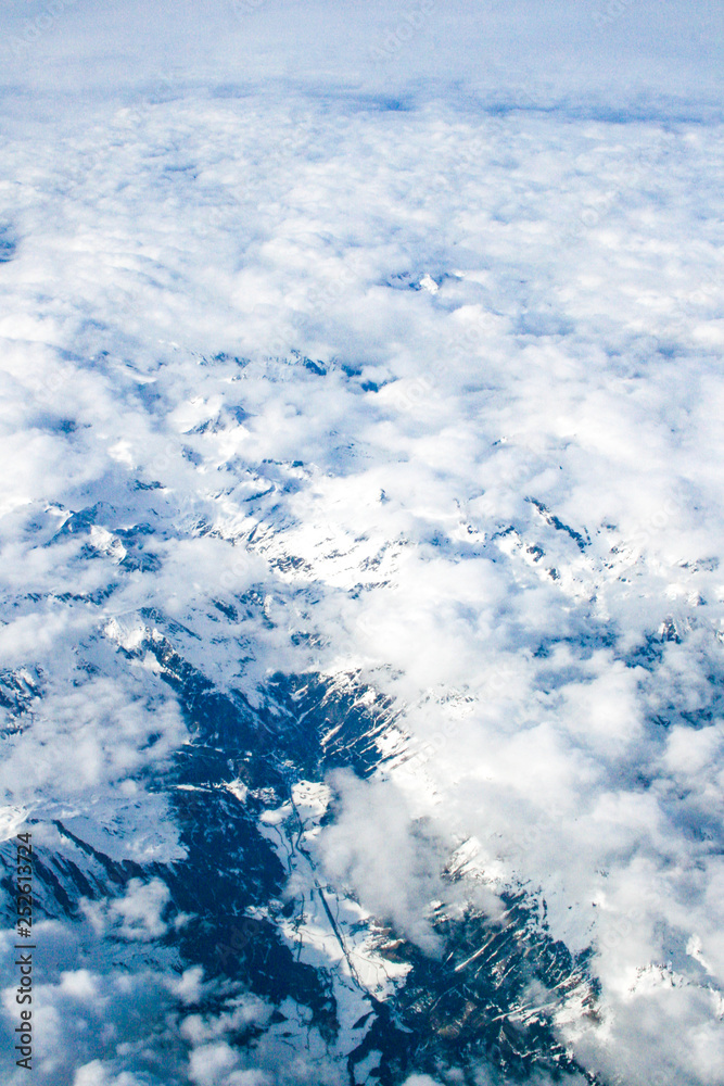 Beautiful clouds and mountains with snow, view from airplane window, background, vertical Beautiful clouds and mountains with snow, view from airplane window, background, vertical