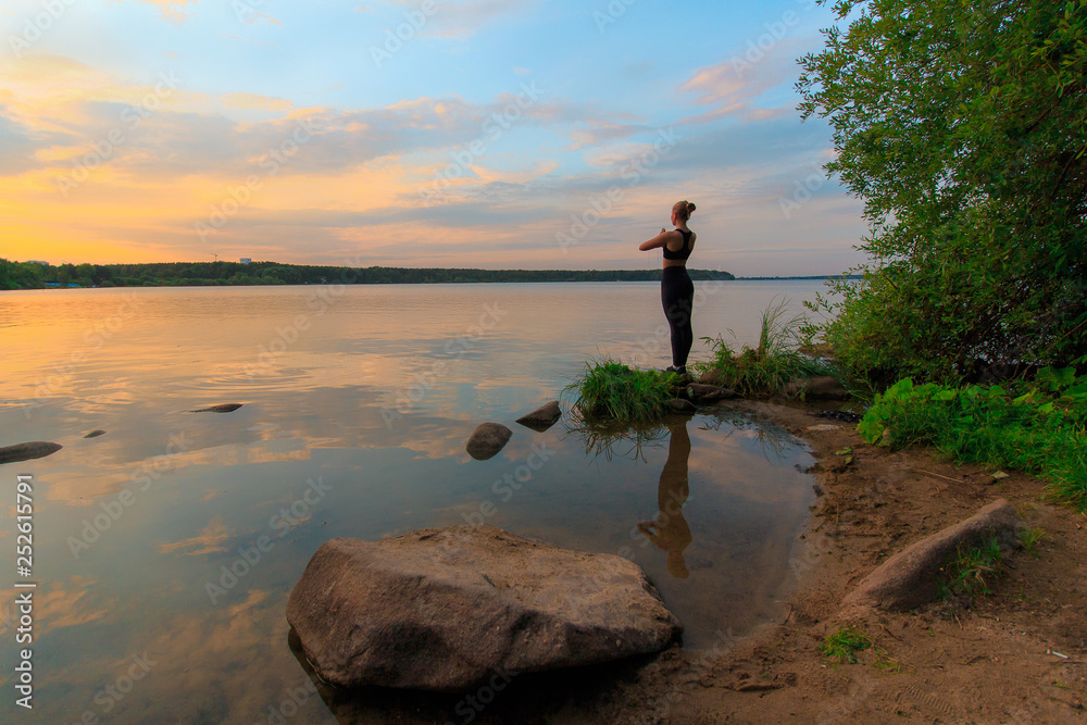 Woman doing namaste, standing on a lake shore at sunset. Yoga nature concept. Woman doing namaste, standing on a lake shore at sunset. Yoga nature concept.