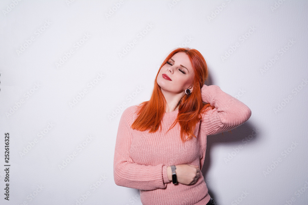 Fototapeta premium Red-haired girl is embarrassed. Portrait of woman at swallow wall